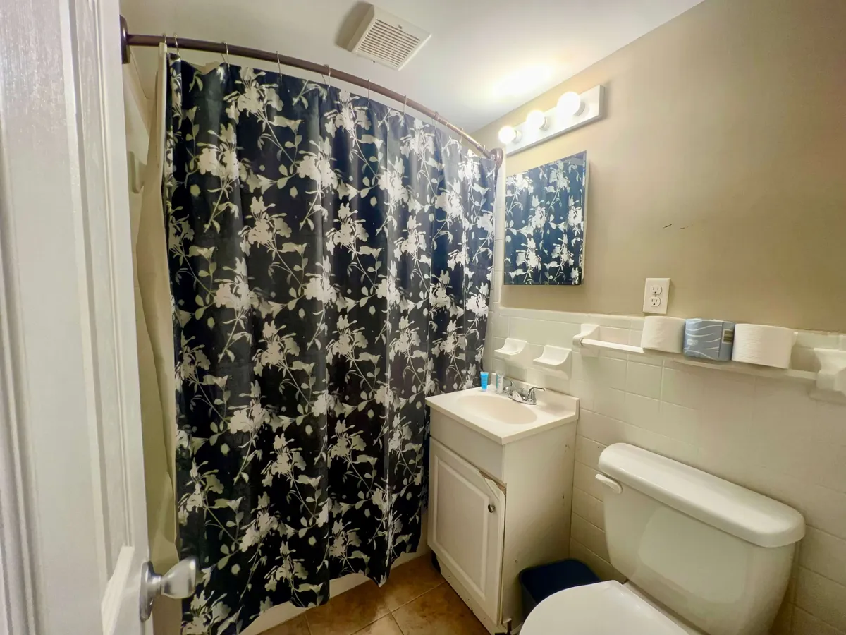 A fresh, clean bathroom with a floral shower curtain, a modern sink area, and a mirror. The space is inviting and practical, supporting both grooming routines and relaxation.